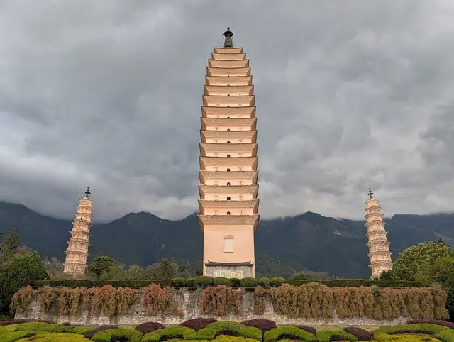 The Three Pagodas of Chongsheng Temple in Dali under a grey overcast sky, with the Cangshan mountains behind them.