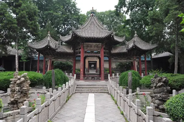 A timber pavilion with upturned grey-tiled roofs in a garden courtyard of the Great Mosque of Xi'an, reached by a stone path.